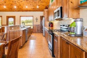 Eine Küche mit Holzausstattung, einer Granit-Arbeitsplatte, einem Herd, einer Mikrowelle und einem Mixer.