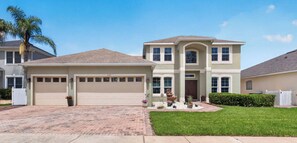 A two-story house with a garage, a driveway, and a well-maintained lawn. - Sunset to Magic 6BR Davenport Home with Private Pool Near Disney (Davenport)