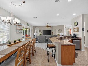 A modern kitchen with a dining area, a built-in island, and a seating area with a sofa. - Sunset to Magic 6BR Davenport Home with Private Pool Near Disney (Davenport)