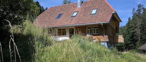 A two-story house with a red-tiled roof, a chimney, and a balcony.