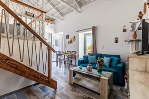 Un vaste espace de vie comprenant un escalier en bois, un canapé bleu, une table à manger et une table basse.