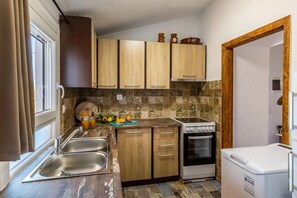 Une cuisine compacte avec des meubles de rangement en bois, un four encastré et un petit réfrigérateur.