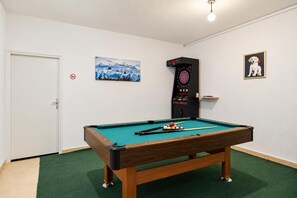 Uma mesa de bilhar com bolas, um alvo de dardos e um quadro com a imagem de um cão.
