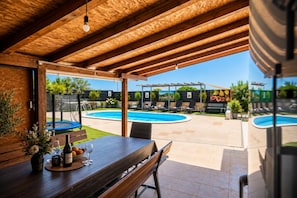 A covered outdoor area with a pool, lounge chairs, and a dining table with wine glasses and bottles. - Villa Odzakovic - Four Bedroom Villa, Sleeps 8 (Nadin)