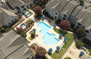 Área residencial com piscina, rodeada de casas, um pequeno jardim e estacionamento.