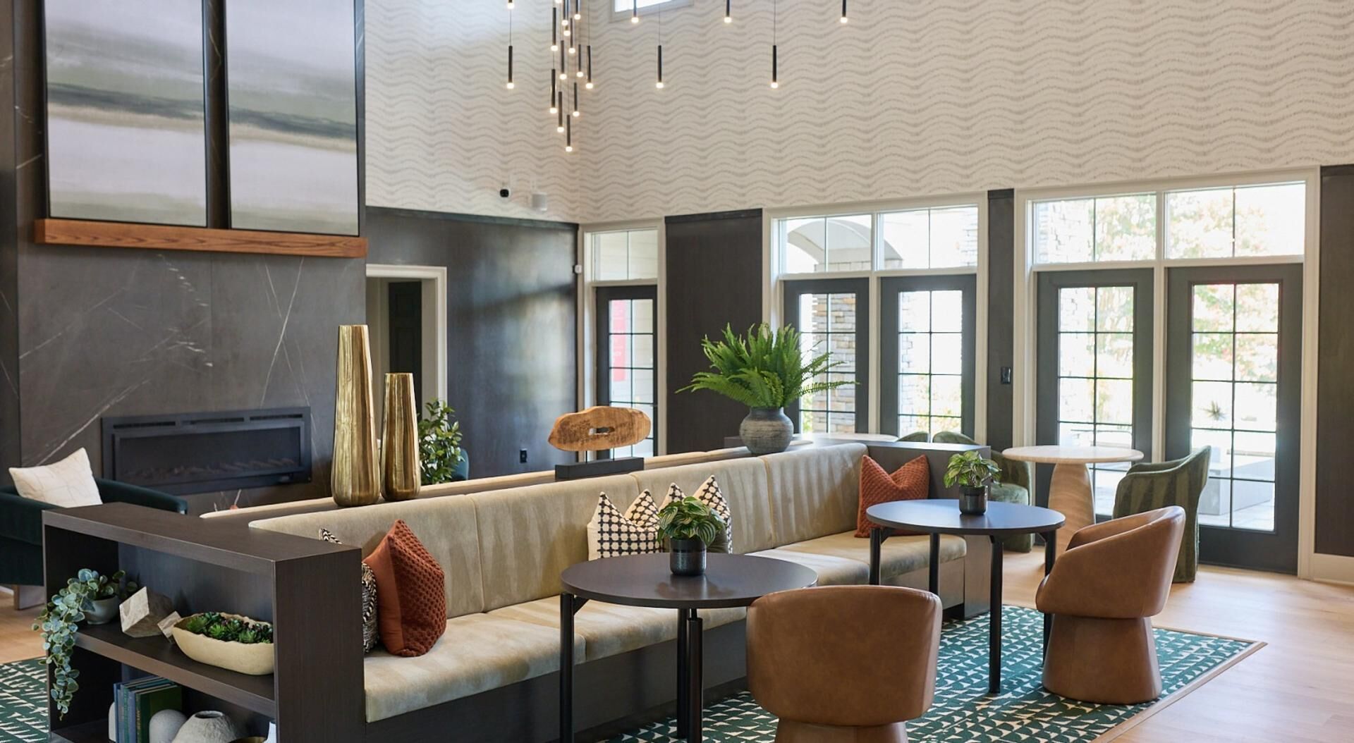 A modern living room with a sofa, coffee table, and chairs, large windows, and a fireplace.