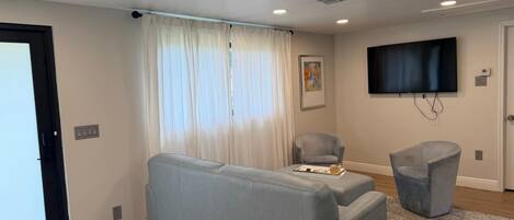 Una sala de estar moderna con un sofá, un sillón, un televisor de pantalla plana y una alfombra estampada.