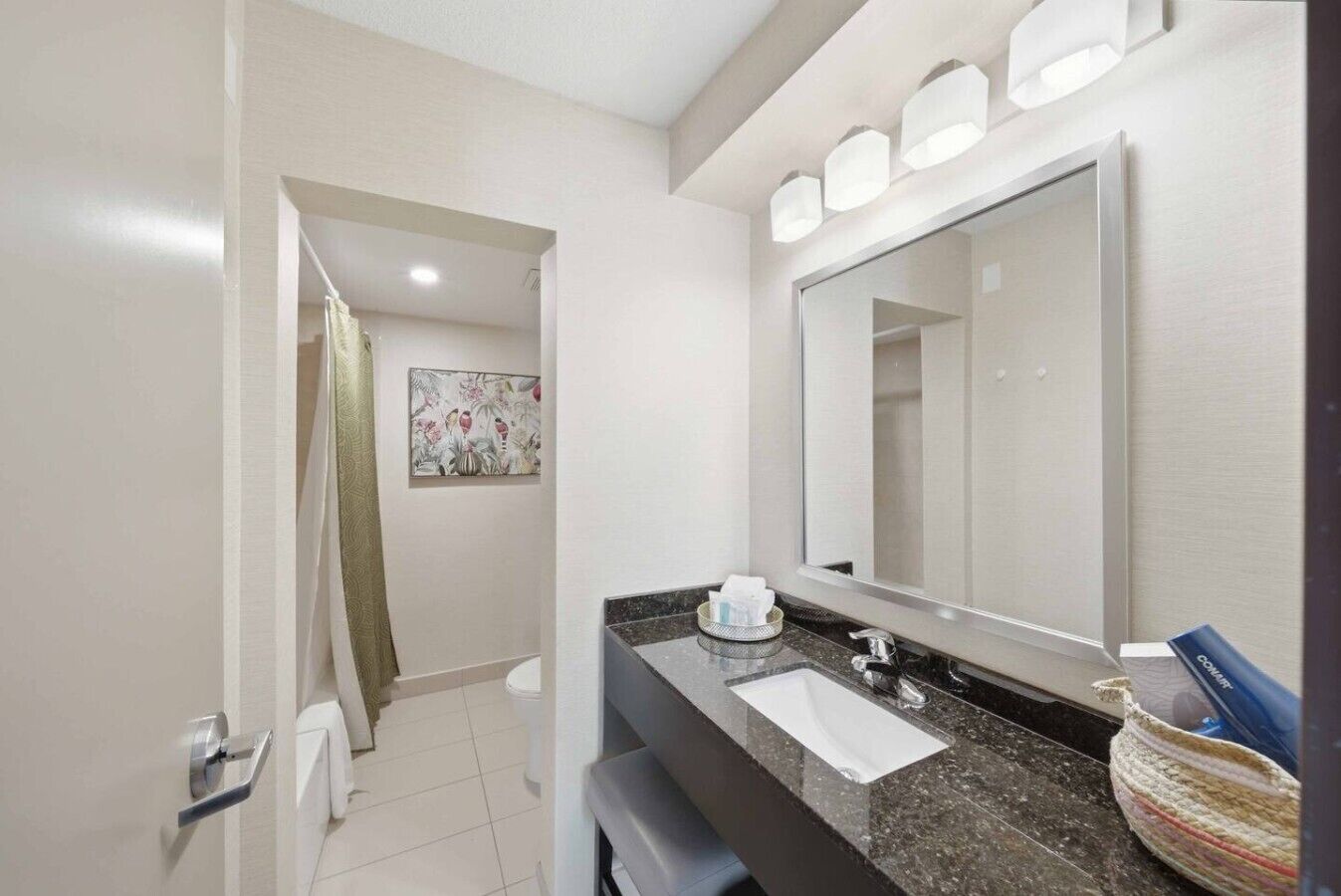 A modern bathroom with a large mirror, a sink, and a shower area.