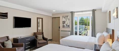 A hotel room with two beds, a flat-screen TV, a desk with a chair, and a window with a view of the outside.