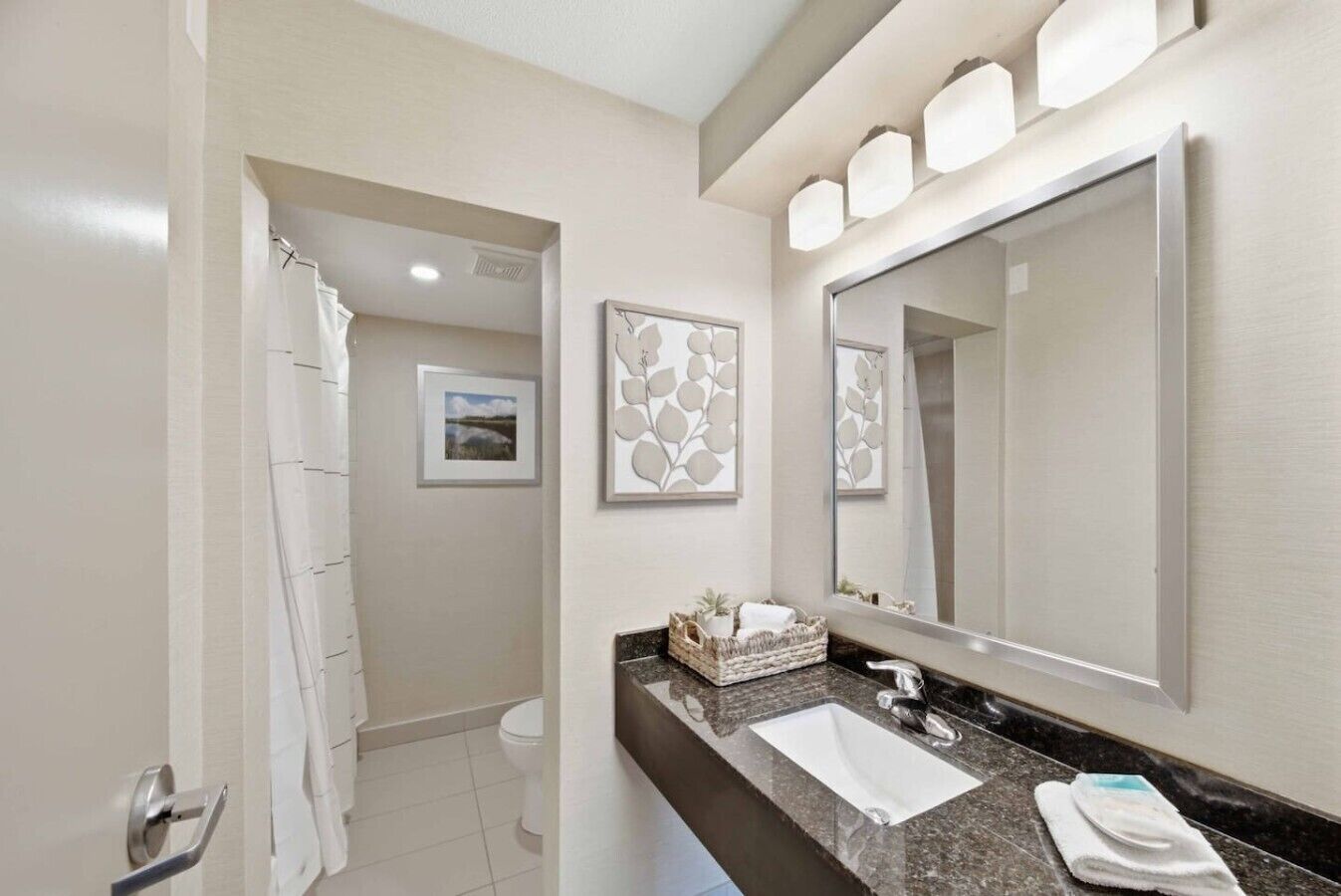 Une salle de bain moderne avec un grand miroir, un lavabo et un espace douche.