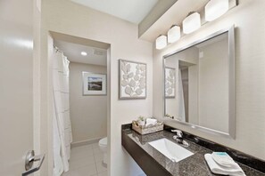 Un baño moderno con un espejo grande, un lavabo y una zona de ducha.