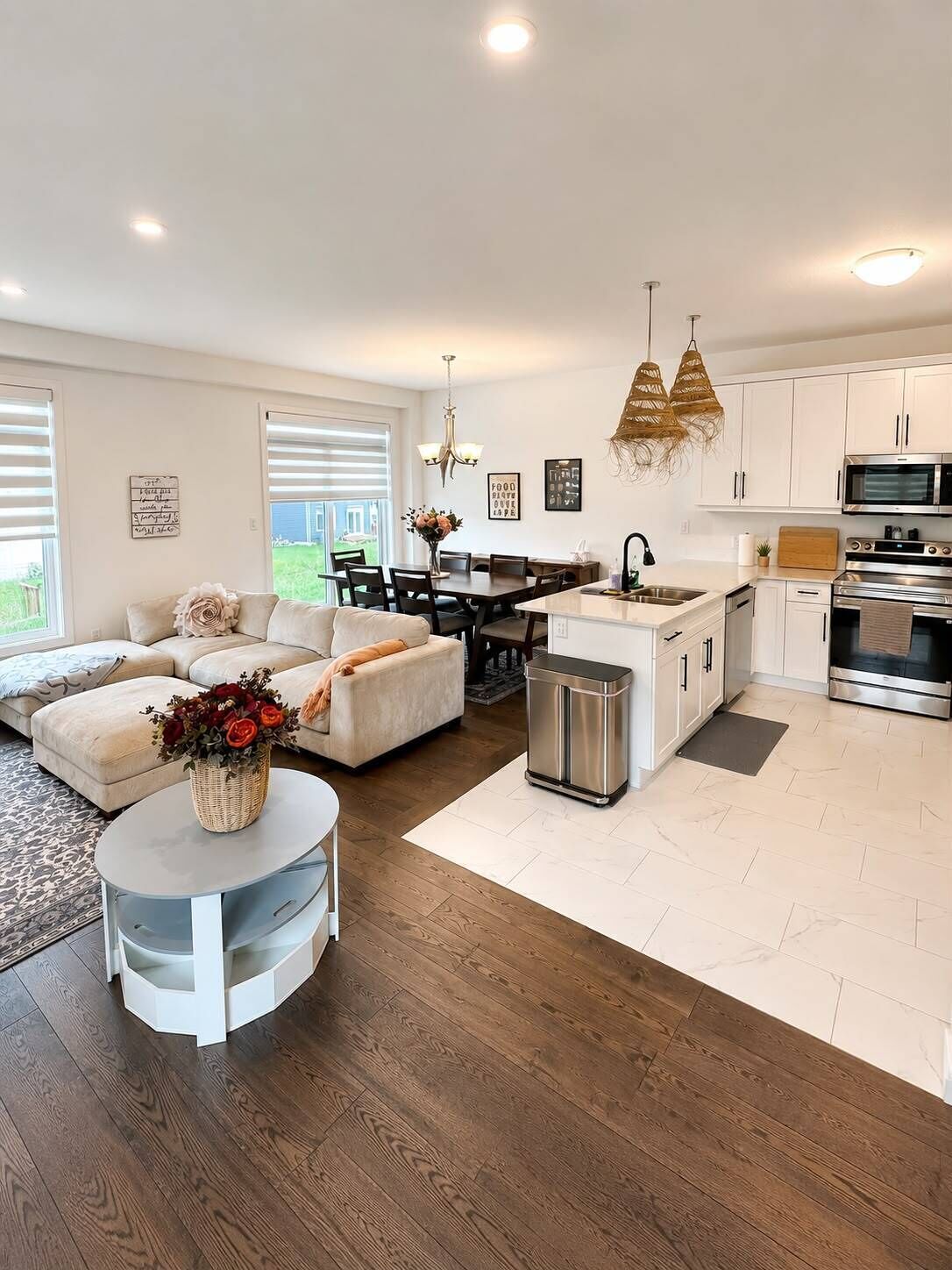 A modern kitchen with white cabinets, stainless steel appliances, and a dining area with a white table and chairs.