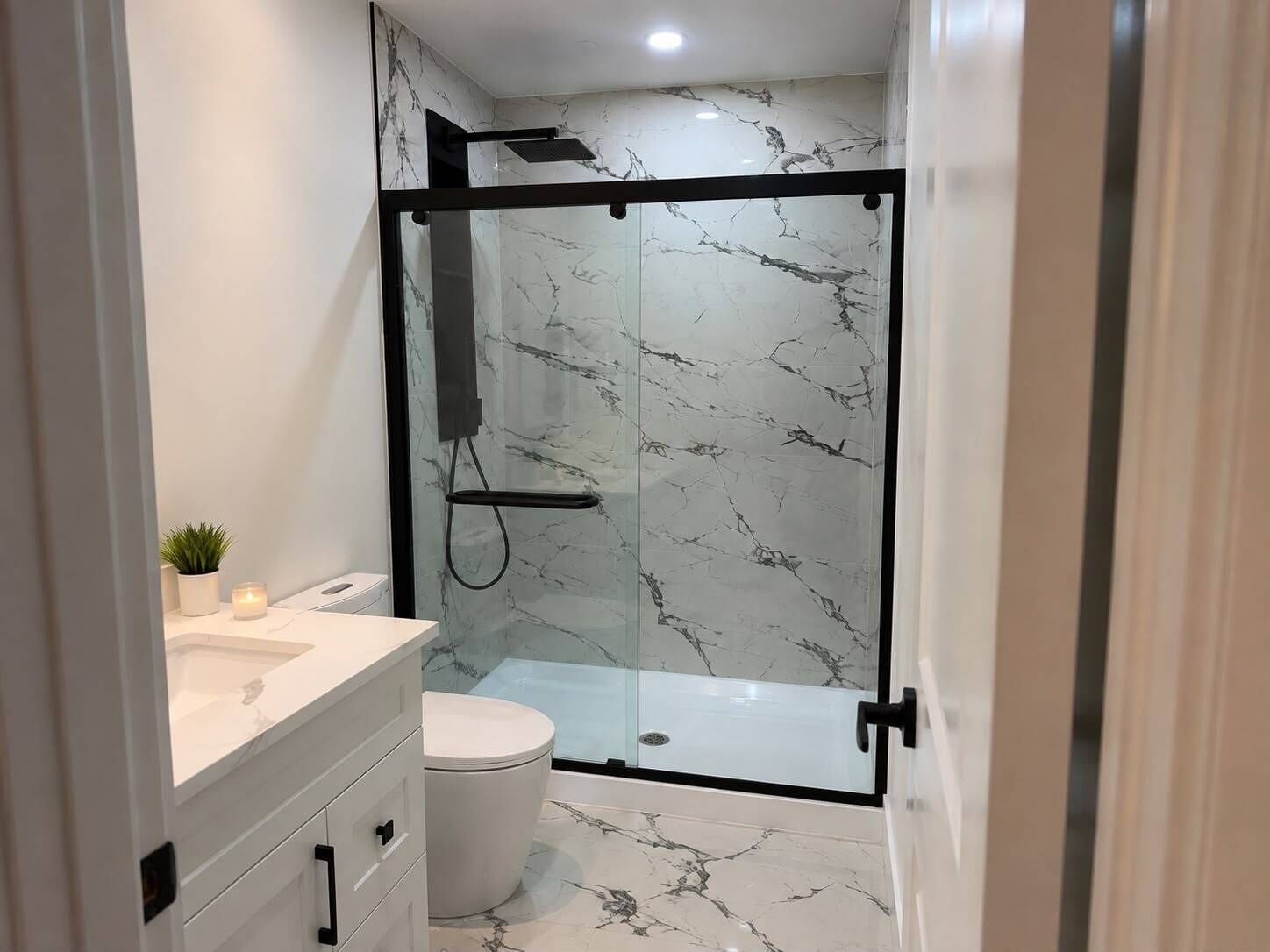 Un baño moderno con ducha envuelta en vidrio, inodoro blanco y tocador con cajones.