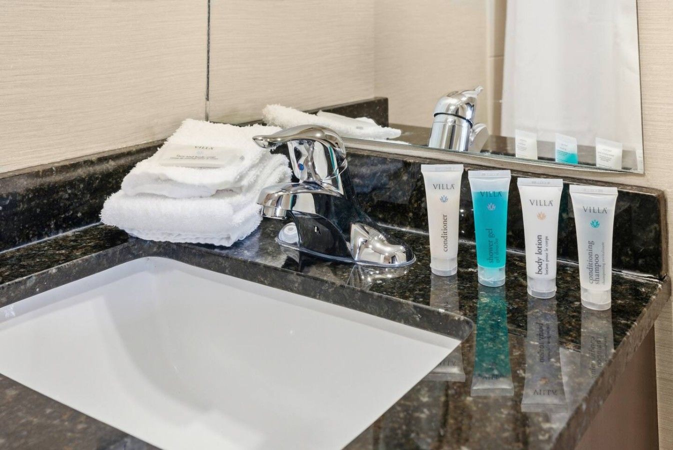 A hotel bathroom with a sink, a towel, and toiletries.
