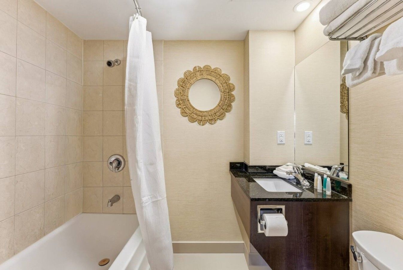 A bathroom with a bathtub, a shower, a vanity with a mirror, and a towel rack.