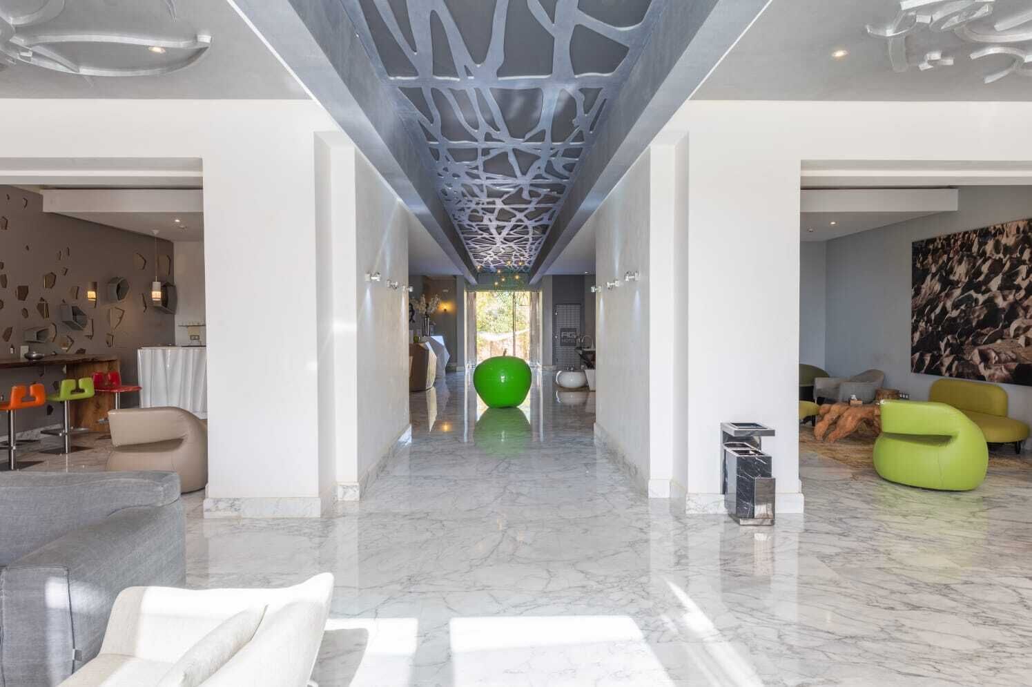 Un intérieur moderne avec un sol en marbre, un ballon d’exercice vert et un fauteuil en forme de sac de haricots jaune.
