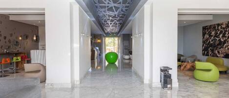 Un interior moderno con suelo de mármol, una pelota de ejercicios verde y un sillón de saco amarillo.