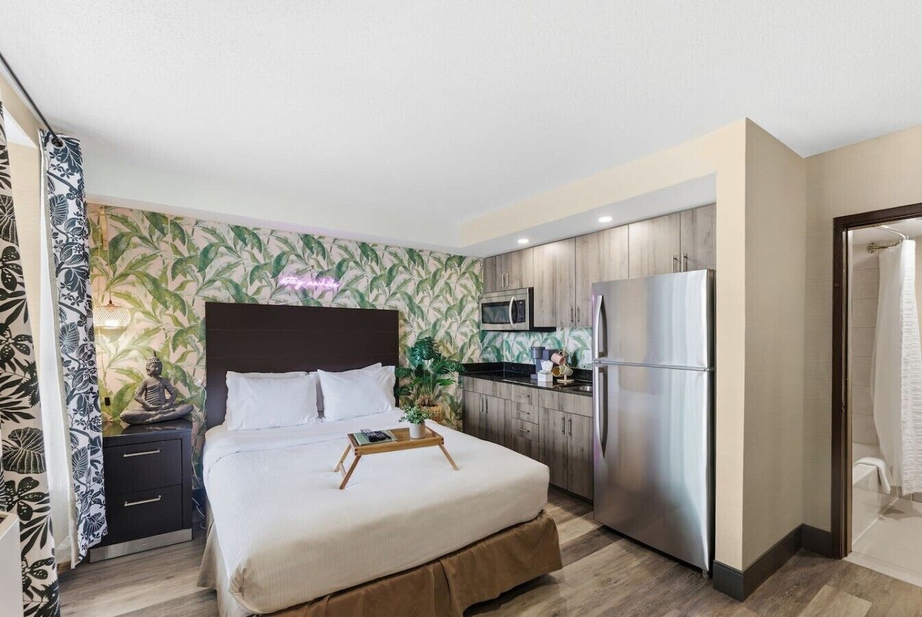 Une chambre d’hôtel équipée d’un lit, d’une table de chevet, d’un four à micro-ondes, d’un réfrigérateur et d’un espace douche.