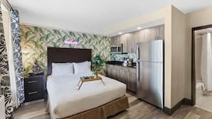 Een hotelkamer met een bed, nachtkastje, magnetron, koelkast en douche.