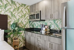 Una cocina compacta con armarios de madera, un refrigerador de acero inoxidable, un microondas y un lavaplatos.
