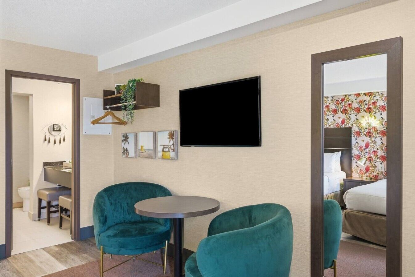 A hotel room with a bed, a TV, a desk with a chair, and a small table with two chairs.