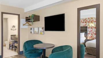 A hotel room with a bed, a TV, a desk with a chair, and a small table with two chairs.