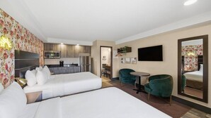 Een hotelkamer met twee bedden, een kitchenette, een eethoek en een televisie.