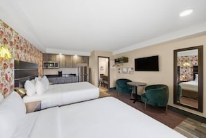 Una habitación de hotel con dos camas, kitchenette, comedor y televisor.