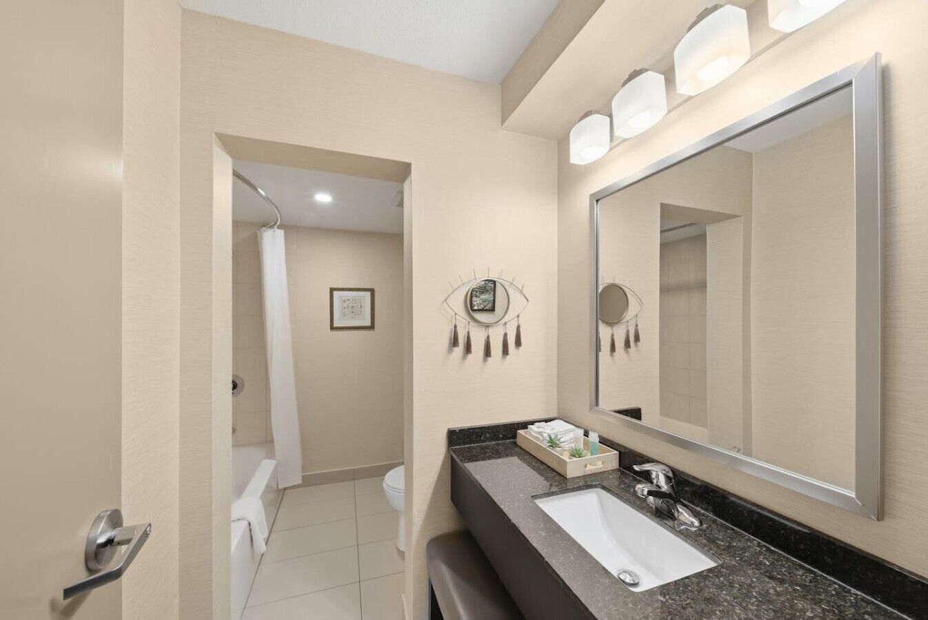 Une salle de bain moderne avec un grand miroir, un lavabo et un espace douche.