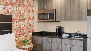 A compact kitchen with a microwave, coffee maker, and a sink.