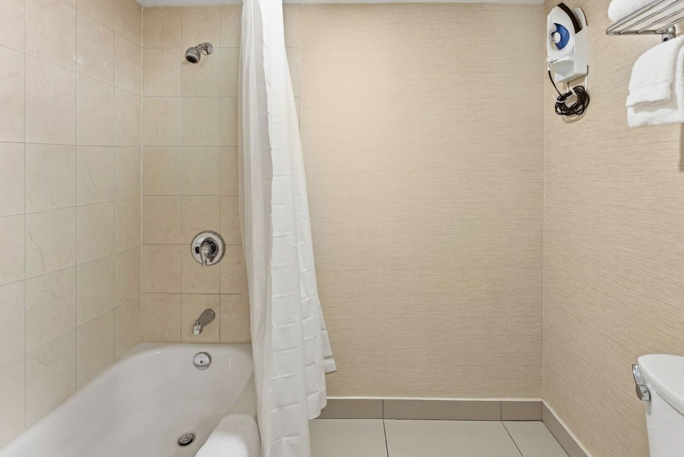 Et badeværelse med badekar, bruser og toilet.
