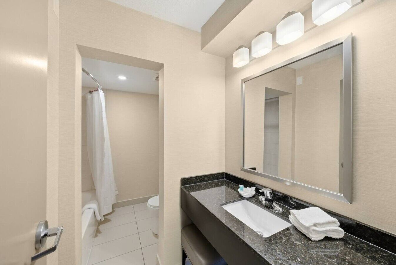 Une salle de bain moderne avec un grand miroir, un lavabo et un espace douche.