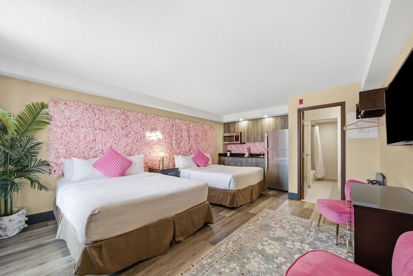 Une chambre d’hôtel avec deux lits, une kitchenette, une télévision et un bureau.