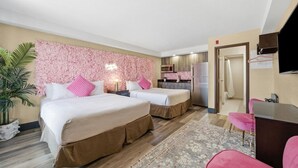 Een hotelkamer met twee bedden, een kitchenette, een televisie en een bureau.