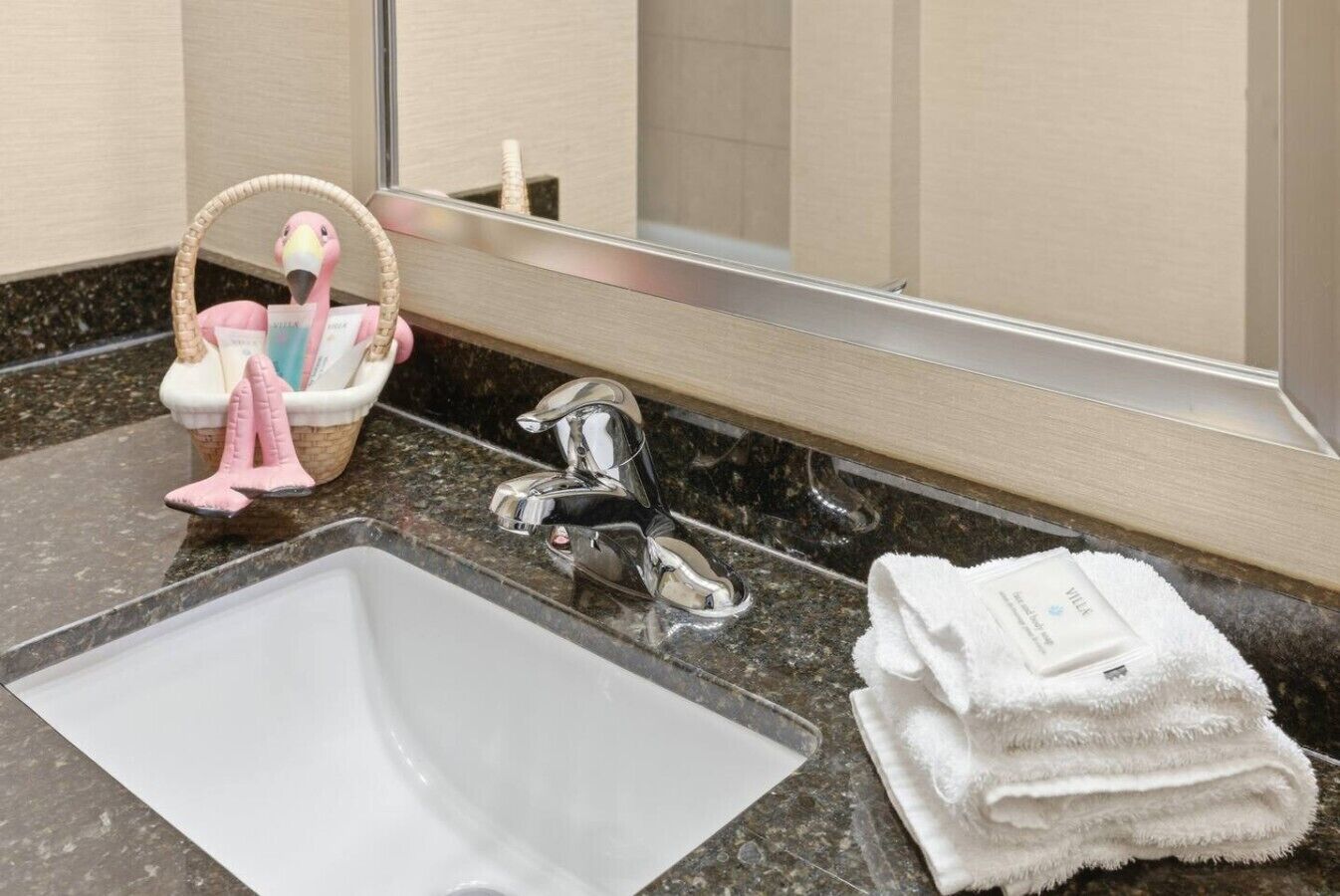 A bathroom with a sink, a mirror, a towel stack, and a basket with toiletries.