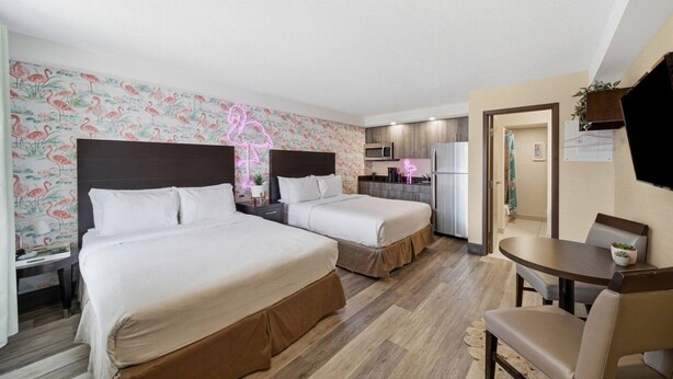 Een hotelkamer met twee bedden, een kitchenette, een eethoek en een badkamer.
