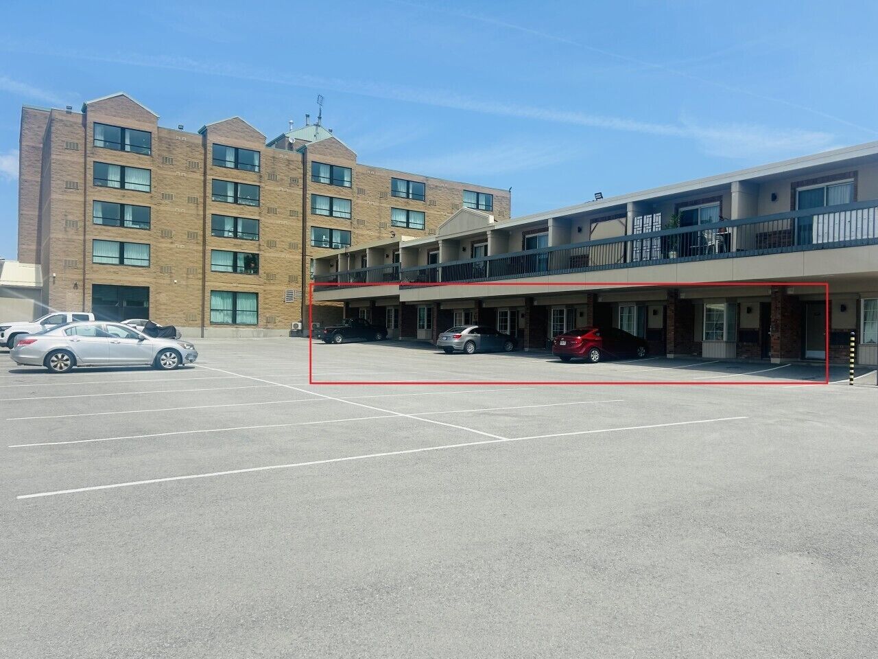 Un immeuble à plusieurs étages avec un parking situé à l’avant.