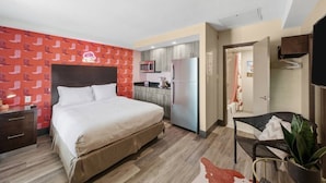 Een hotelkamer met een bed, een kitchenette, een badkamer en een zithoek.