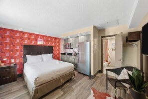 Una habitación de hotel con cama, kitchenette, baño y zona de estar.