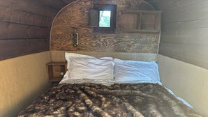 A bed with a patterned blanket, a wooden headboard, and a small window.