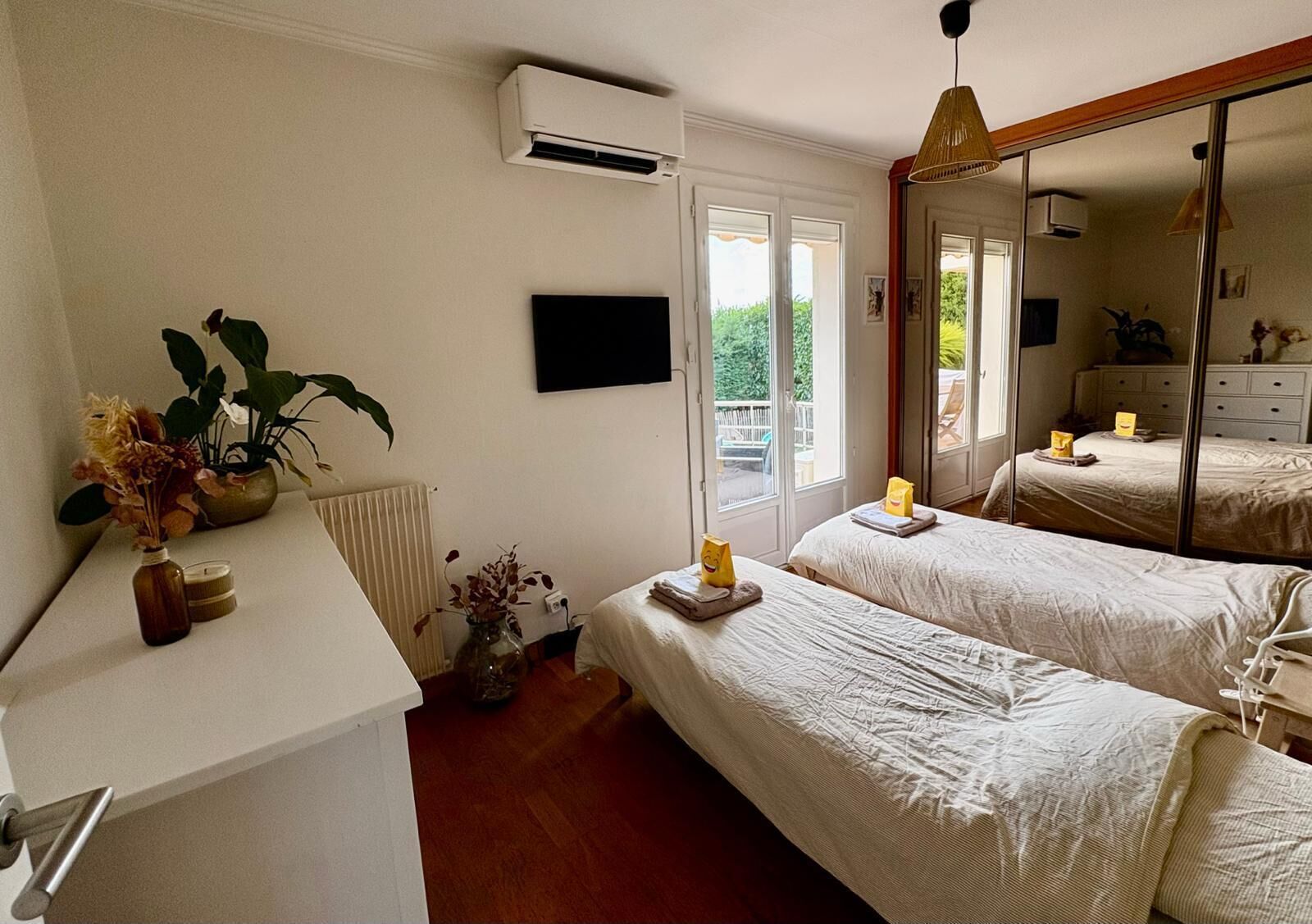 Une chambre avec deux lits, un radiateur, une fenêtre et un miroir.