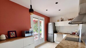 A modern kitchen with white cabinets, a stainless steel refrigerator, a microwave, and a coffee maker on the counter.