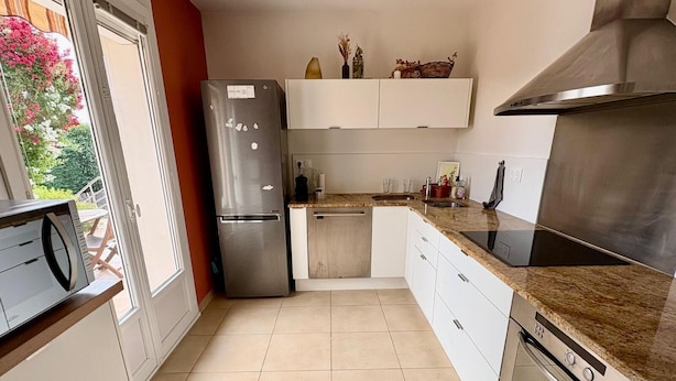 Una cocina moderna con horno integrado, refrigerador de acero inoxidable y encimera con pileta.