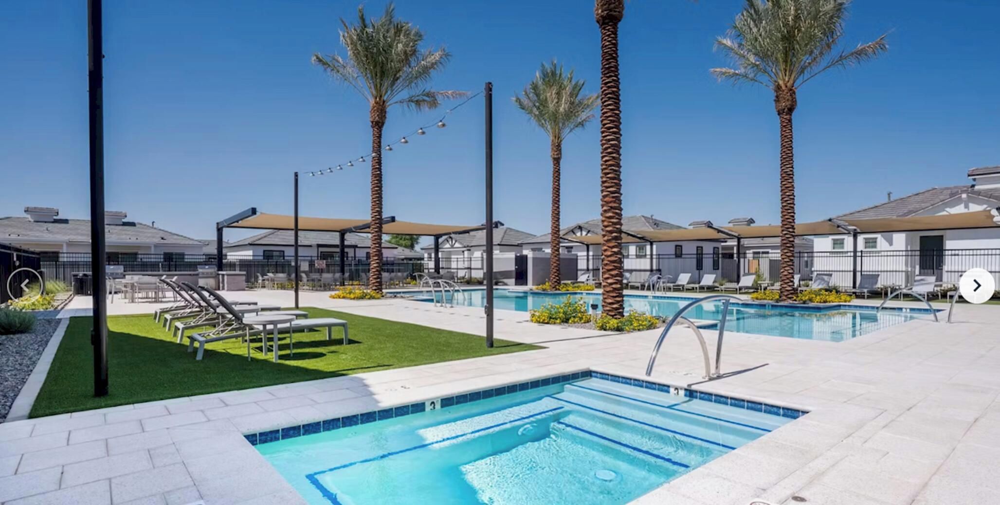 A pool area with multiple pools, lounge chairs, and palm trees.