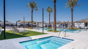 A pool area with multiple pools, lounge chairs, and palm trees.