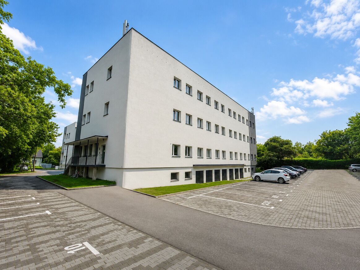 Ein modernes Gebäude mit Parkplatz und einer Reihe geparkter Autos.