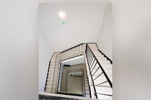 A modern staircase with a geometric design, a handrail, and a light fixture on the ceiling.