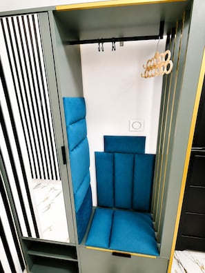 A room with a blue upholstered seating area, a vertical striped panel, and a hanging light fixture.