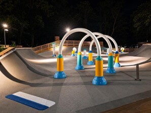A skate park at night with ramps and colorful safety bollards.