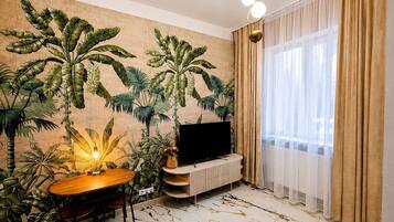 Un soggiorno con televisione a schermo piatto, un tavolo da pranzo e un affresco con motivi tropicali.